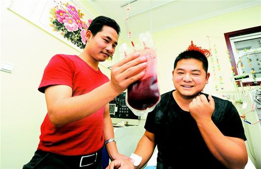 图为：工作人员向梁啸（右）展示造血干细胞混合液。