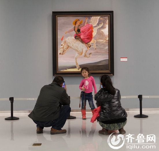 一对夫妻为女儿在美术作品前拍照。