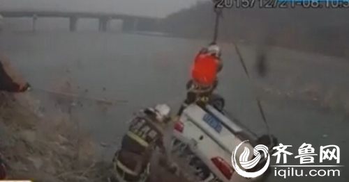 消防战士爬到沉没车辆上方，挂上挂钩营救。