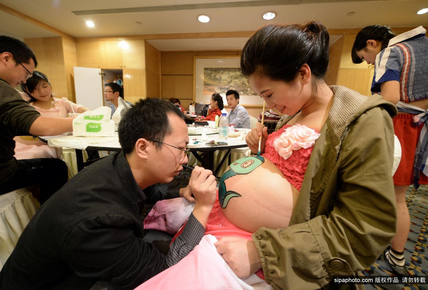 彩绘大赛.准妈妈们在自己挺起的肚子上绘画各种图案,代表着高清图片