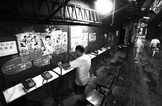 图为：6月20日晚，汉正街一位打工者在公话超市联系家人。