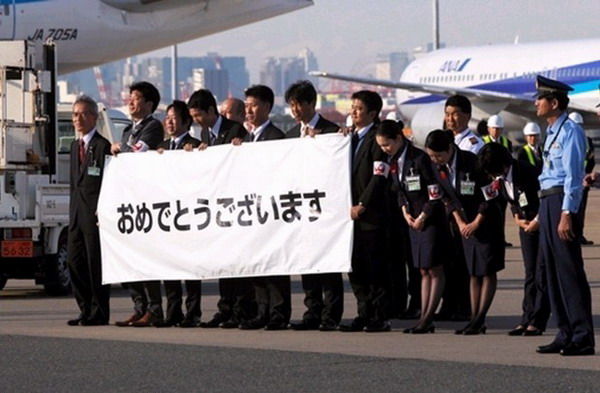 9日下午，航空公司职员在羽田机场迎接安倍晋三首相回国（网页截图）
