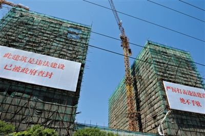 7月16日，北京宋庄徐宋路西侧几栋建筑上悬挂着巨幅标语，标明该建筑为小产权房，属于违法建筑。新京报记者吴江摄