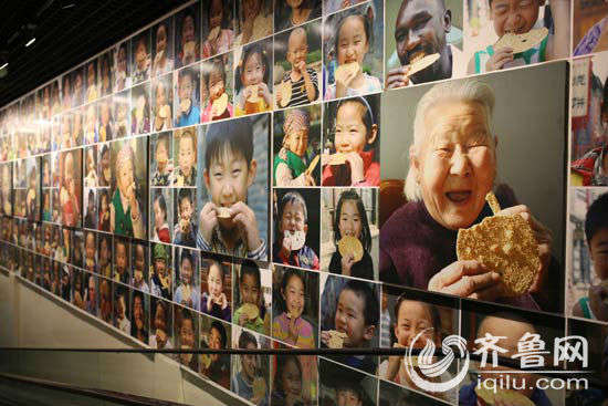 周村烧饼博物馆内通往烧饼制作区的电梯两侧，挂满了百余幅游客吃烧饼的欢乐笑脸。