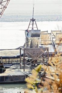图为：可疑的采砂船停泊在汉江边采砂船正在卸载江砂（摄影：记者李辉）