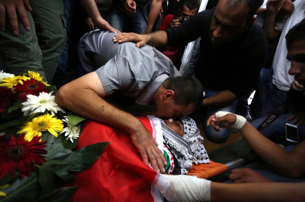冲突中一名13岁少年被打死,他的父亲趴在遗体上痛哭.