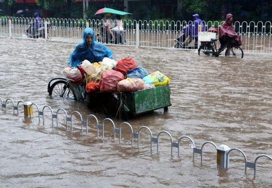 6月2日，在衡阳市船山大道，一名市民推着三轮车行进在积水的街道上。新华社发(曹正平 摄)