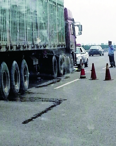 被撞交警倒在肇事货车车轮前(画圈处)