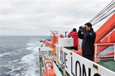 23日，“雪龙”号上的科考队员向海面瞭望，他们正开赴搜救区。新华社发