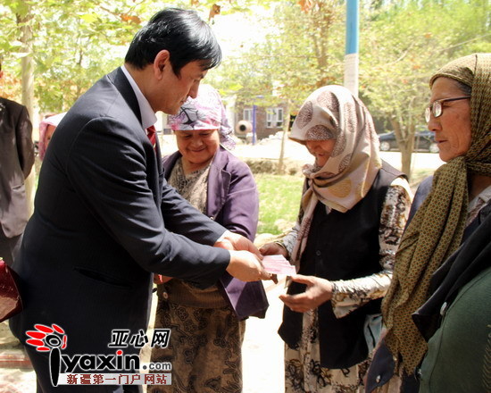 中国爱心工作委员会副主席艾买·依民提为和田市肖尔巴格乡阿克兰干村村民赠送慰问金。诸葛瑞金摄