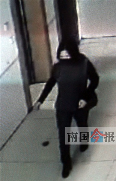 女子戴着口罩走进旅社大厅。(根据监控录像翻拍) 记者 周群能 摄