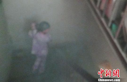 大火吓得抱小孩的妈妈腿脚发软，在楼梯间内无法挪动。张建平 摄