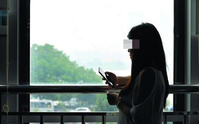(6月4日，柳惠（化名）在窗前翻看手機上的信息。她離開楊國雄後，每天都要收到大量騷擾信息，這讓她不勝其擾。記者 田超 攝)