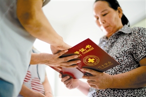 母亲李群从红十字会义工手中接过器官捐献的荣誉证书。