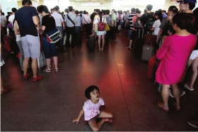 6月24日,高铁长沙南站售票厅,小女孩坐在地上无聊地等待。当日,因高铁设备维护,致途经长沙的26趟G字头的高铁列车停运,大量列车晚点,旅客不得不在售票厅里排队退票和改签。图/记者陈正