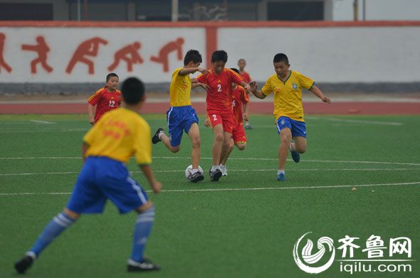 学生们身着新衣,驰骋在足球场上。