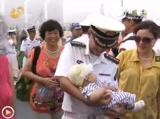 一位海军士兵抱着年幼的孩子，满怀欣喜。