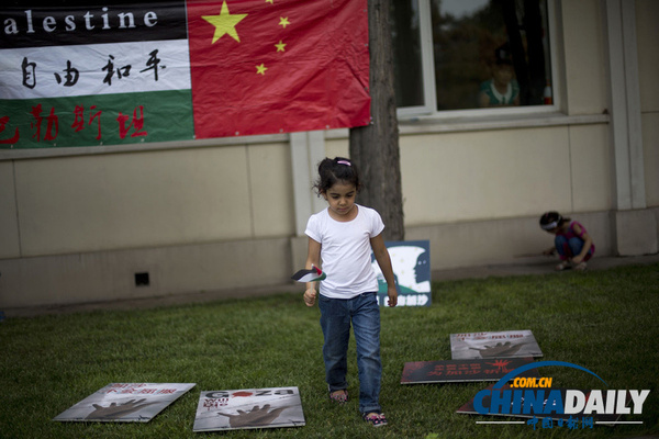 2014年7月18日，中国北京，一名小女孩手持伊拉克国旗在抗议活动现场。当天，多国民众在巴勒斯坦驻北京大使馆外游行，抗议以色列攻击加沙地带。（图片来源：东方IC）
