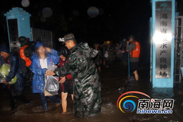 海南军区某炮兵团的官兵冒雨趟着一米多深的水进入厂区转移被困群众。(军区供图)