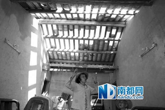 23日，海南省文昌市翁田镇下山良村，83岁的张芳莲(左)和84岁的黄保文在自家受损的房子里。屋顶瓦片少了一半。南都记者 谭庆驹 摄
