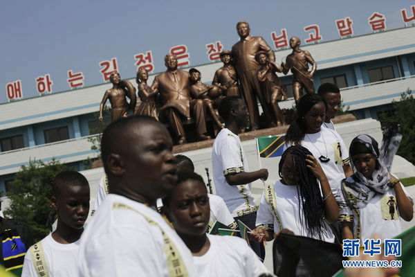 　　当地时间7月29日，朝鲜元山，来自坦桑尼亚的学生参加朝鲜松涛园国际少年团夏令营，他们经过金正日和金日成的雕像。（图片来源：东方IC）