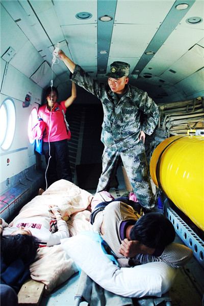 图为鲁甸地震救援中，陆航旅官兵在直升机内为伤员高举吊瓶。记者 薛玉斌摄