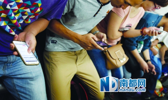 ←地铁上,一排乘客在低头看手机。