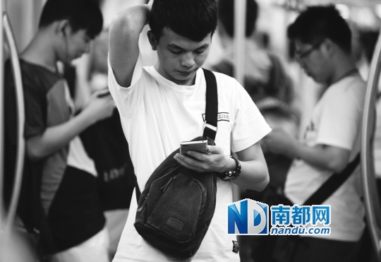 ↓在广佛地铁狭窄的车厢里,几名乘客不约而同地低头看手机。