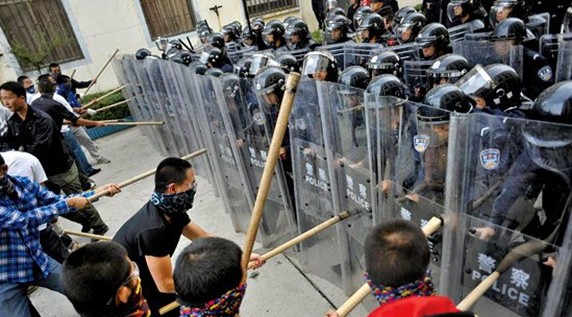 闹事人员持木棍与特警对峙。