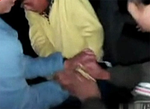 一名打人女孩还专门负责抓住黄衣女孩的双手。（视频截图）