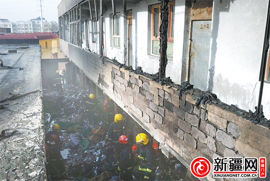 11月24日15时03分,在火灾现场,消防人员正在搜索余火。