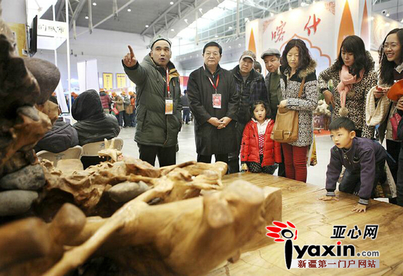 11月29日，在新疆国际会展中心，巴州千木野根雕有限公司总经理阿布都沙拉木·阿不力孜在向观众介绍自己的名为《中国梦》的根雕作品。（亚心网记者 李雄心摄）