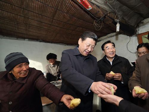 2012年12月30日,习近平在河北省阜平县龙泉关镇骆驼湾村困难群众唐荣斌家,与随行人员一起品尝蒸土豆。