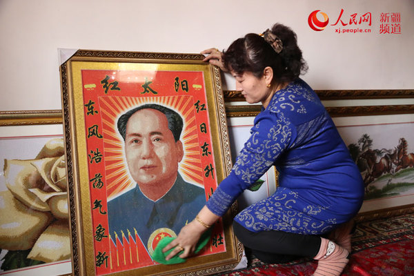 阿依仙木古丽正在认真擦拭装裱起来的《毛泽东主席像》。徐蒙摄