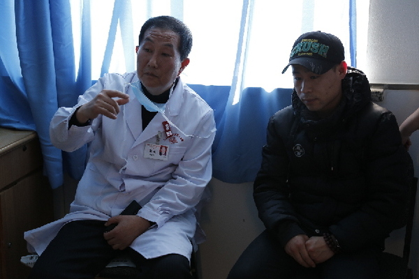 　　山西大二院副院长张进在给李翔的丈夫张海林介绍妻子的病情。（李昊炯 摄）