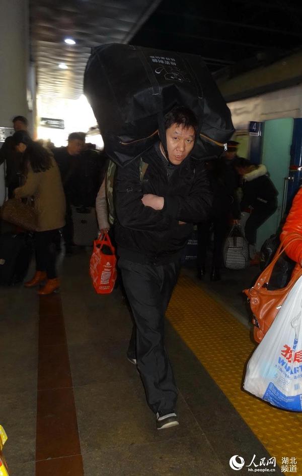 2月10日16：15北京西站男子用下巴牵拉着后背上的行李包大步赶车