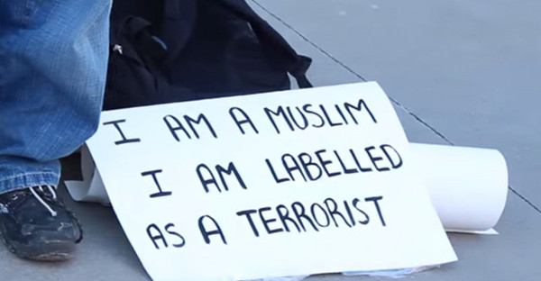 男子身边的纸牌写着：“我是穆斯林，却被贴上恐怖分子的标签。”（图片来源：美国媒体）