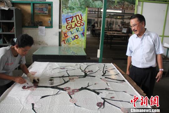 叶晟源在工厂亲自指导工人用彩色玻璃精细贴画中国梅花。　顾时宏　摄