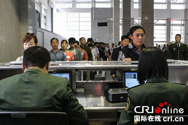 　　等待办理出境手续的游客排起长龙。摄影 屈景峰