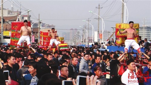 “僮身”赤裸上身乘坐刀轿巡游，围观群众挤满街道