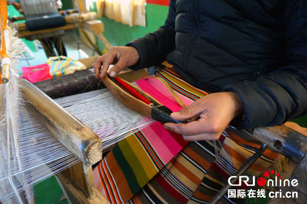 纺锤在工人手中左右飞舞，细密平整的氆氇慢慢显现出来 摄影：刘倡　　