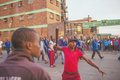 17日，在南非约翰内斯堡，一名当地男子手持棍棒呼喊口号。