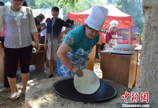 图为一名锡伯族民众正在锅里烙饼。　孙亭文　摄