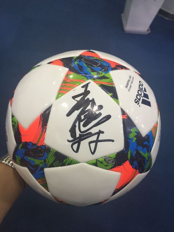王健林接受新华网足球队赠送礼物 在足球上签