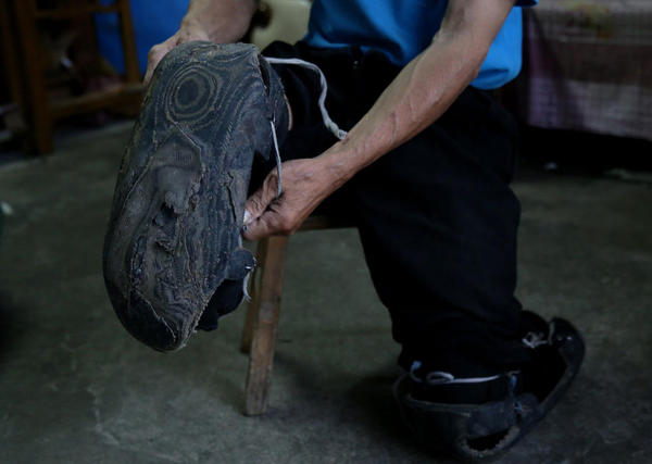 虽然家庭困难，收入也不高，但是章日辉告诉记者，他相信用自己的双手能改变命运。图为章日辉为了方便自己行走，用轮胎皮制作了一双特殊的“鞋”。