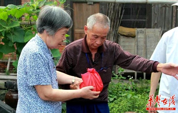 裘彩贵女儿裘爱卿(右者)手捧从春华山上取的泥土。