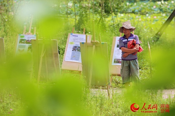 一名当地的村民在观看外地游客的摄影、绘画展。