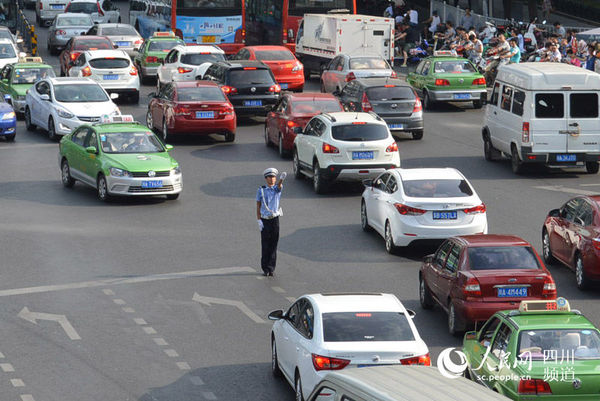 8月3日，成都顺城大街与蜀都大道路口，一名交警冒着烈日疏导交通。（王波 摄）