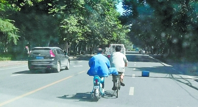 一只脚搭在自行车后座 男子马路上玩特技,好险