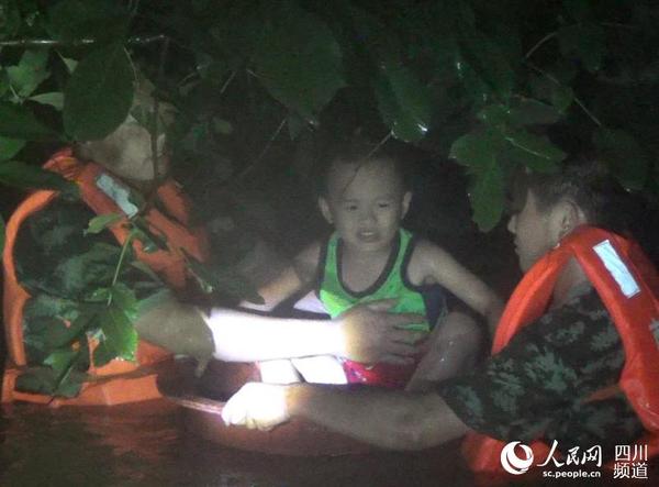 8月17日21时30分许，南充市高坪区龙门镇三岔路口一居民小区被淹，消防官兵正营救一被困5岁小孩。（欧栖羽 摄）